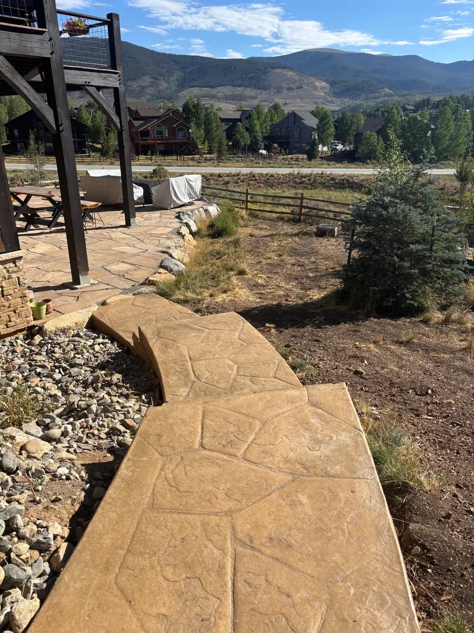 Stamped concrete walkway curving down from a patio with mountain views